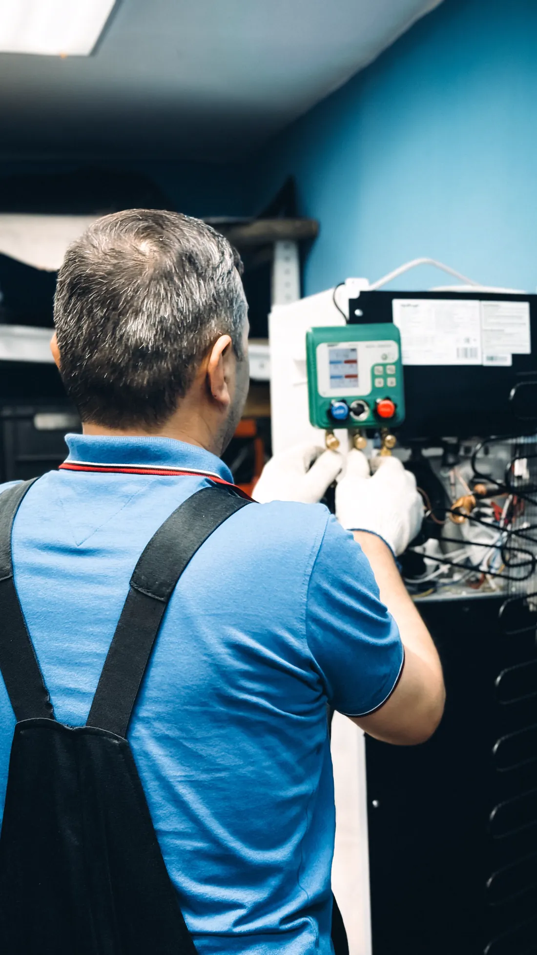 Técnico de espaldas midiendo la presión del circuito de un frigorífico con un manómetro digital