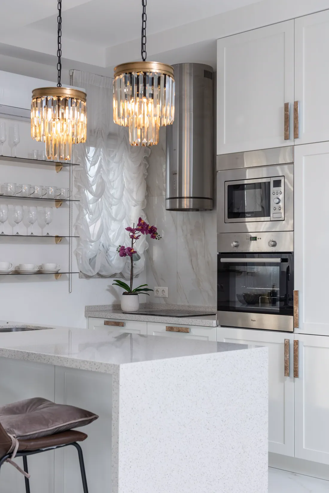 Cocina blanca con isla, horno y microondas empotrados en columna y campana de acero